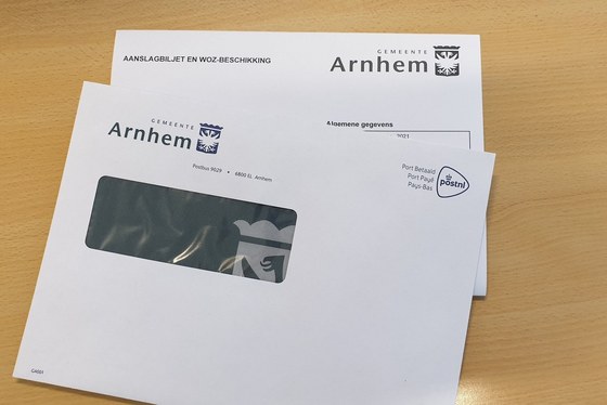 Foto van een witte envelop en een aanslagbiljet namens de gemeente Arnhem